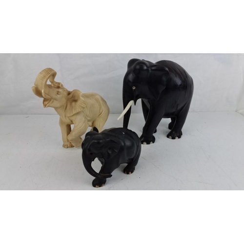 64 - Three carved elephant figurines, varying in colour and size.