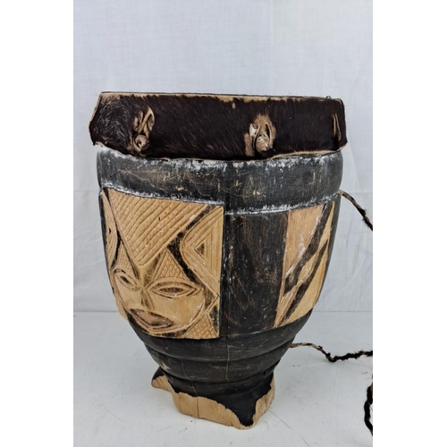 9 - African tribal drum, hand-carved wood with animal hide drumhead, decorated with mask motifs.