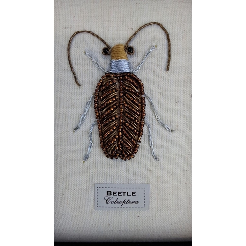 93 - Framed beetle artwork with intricate bead detailing on a fabric linen background. Labelled 