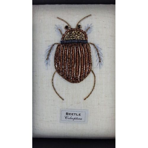 96 - Framed fabric artwork featuring a handcrafted beaded beetle labeled 