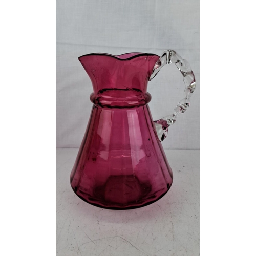 187 - Hand-blown cranberry glass pitcher with an intricate clear twisted handle. The pitcher features a fl... 