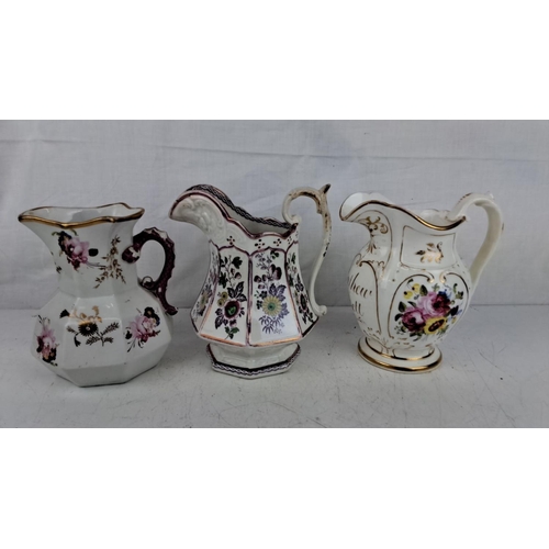 197 - A collection of three antique porcelain pitchers, each featuring hand-painted floral motifs and gilt... 