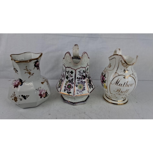 197 - A collection of three antique porcelain pitchers, each featuring hand-painted floral motifs and gilt... 