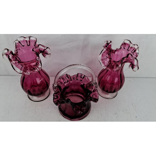 198 - Set of three ruby art glass pieces. Includes two vases and one handled basket, each showcasing intri... 