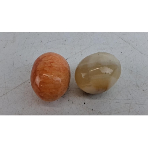 223 - Pair of polished gemstone eggs: one in orange calcite and one in beige onyx. Smooth finish highlight... 