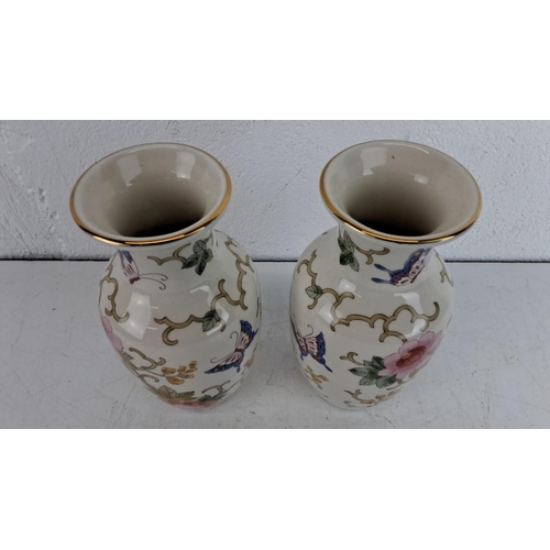 239 - Pair of small porcelain vases with floral and butterfly motifs, accented with gold trim.