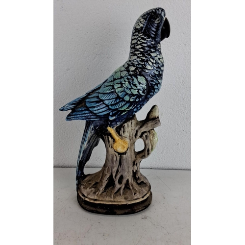 240 - Hand-painted ceramic parrot figurine perched on a branch, featuring vibrant blue and green feathers.... 