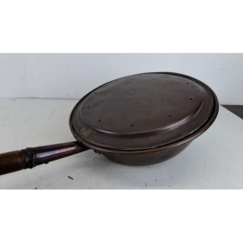 348 - Antique copper bed warmer with wooden handle, featuring a hinged lid with ventilation holes.