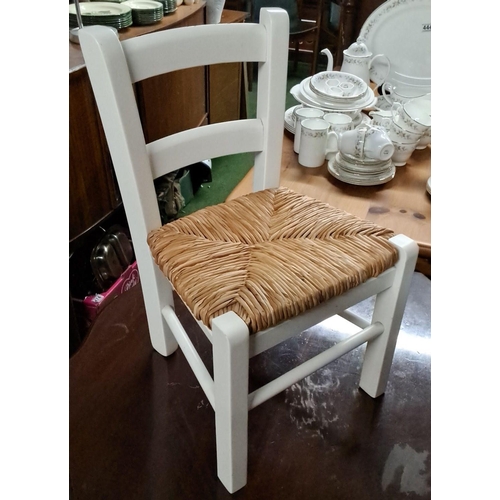 446 - Child-sized wooden chair with a white-painted finish and woven natural fiber seat.