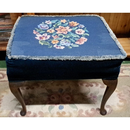 453 - Small upholstered footstool with floral needlepoint on blue fabric. It features a wooden frame and c... 