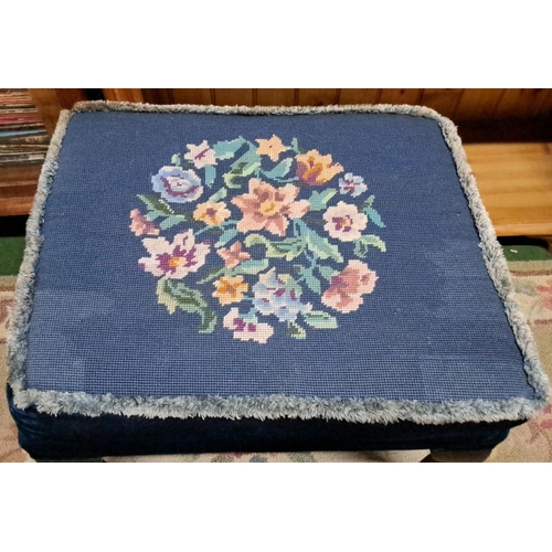 453 - Small upholstered footstool with floral needlepoint on blue fabric. It features a wooden frame and c... 