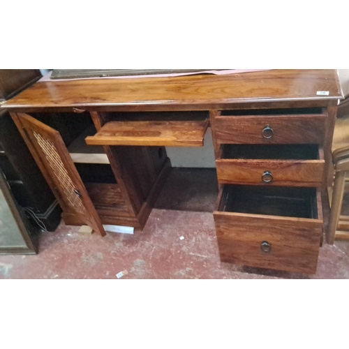 20 - Modern wooden desk with a lattice cabinet door, three drawers, and a sliding keyboard tray. It is a ... 