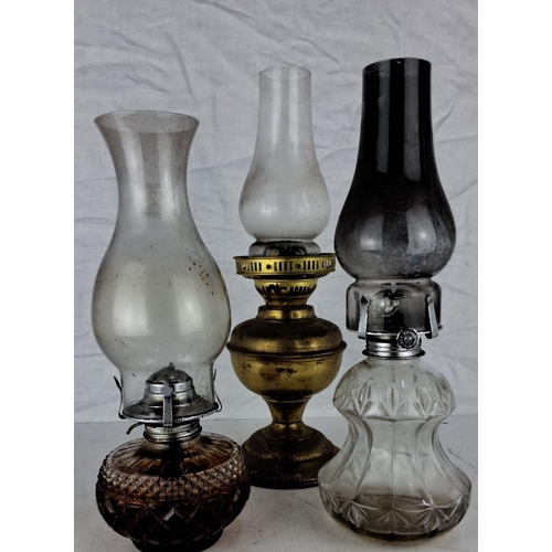 22 - Set of three vintage oil lamps featuring brass and glass bases with intricate detailing.