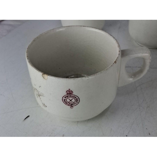 26 - Four ceramic mugs from the Royal Portrush Golf Club, white with a red club emblem.