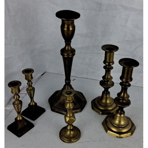 43 - Set of six vintage brass candlesticks with assorted elegant designs and varying heights.