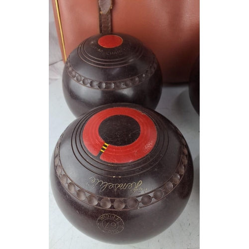 80 - A set of four lawn bowls comes with a carrying case. Each bowl is marked No. 67 with red and black d... 