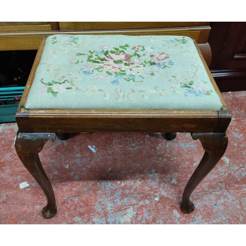 460 - Mahogany footstool with floral needlepoint upholstery. Features elegantly curved cabriole legs.