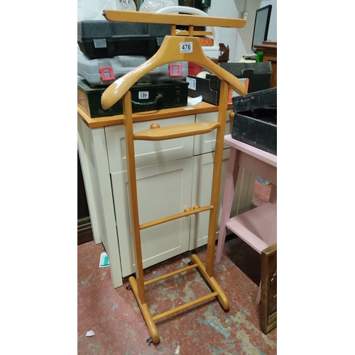 476 - Wooden valet stand with hanger and trouser bar. Features caster wheels for mobility.