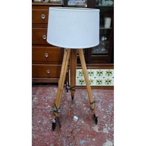 482 - Vintage tripod floor lamp with wooden legs and a white fabric lampshade. This item features a unique... 