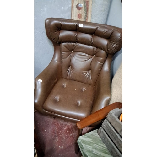 492 - Mid-Century Modern brown faux-leather lounge chair features tufted detailing and wooden armrests. It... 