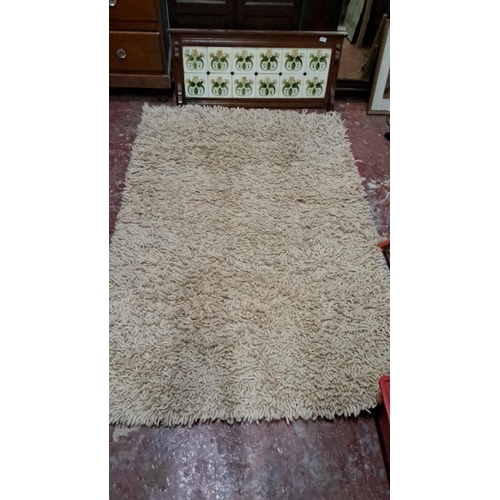 496 - The item is a shag pile area rug in a cream color. It is approximately 6x9 feet and has a woven back... 