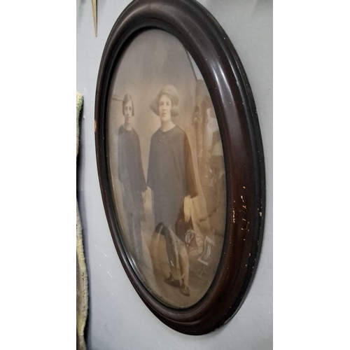 497 - Oval sepia photograph of two young women in dark clothing, housed in a dark wooden frame from the ea... 