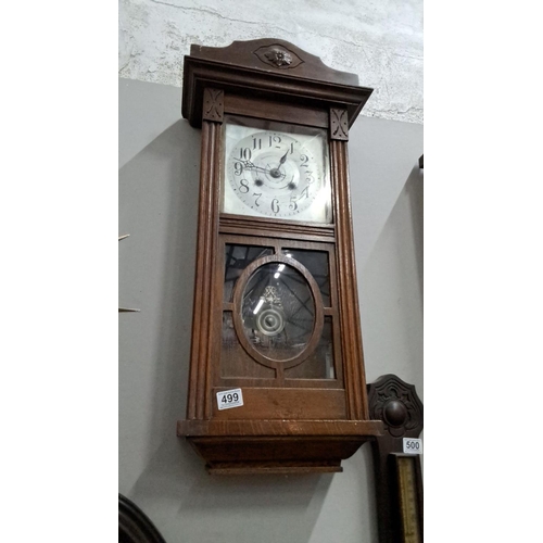 499 - wooden wall clock with glass pane and pendulum. The clock features ornate carved details and a tradi... 