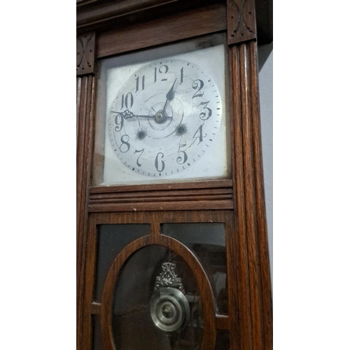 499 - wooden wall clock with glass pane and pendulum. The clock features ornate carved details and a tradi... 