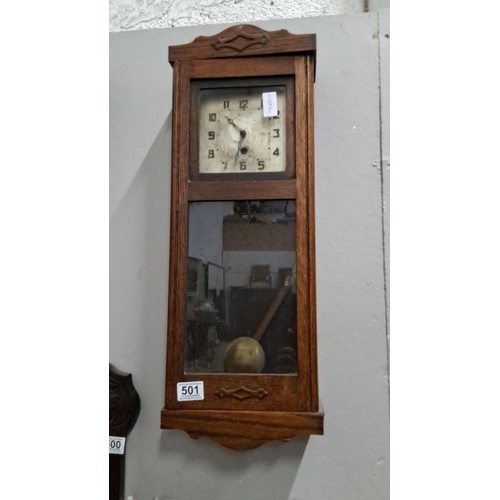 501 - Early 20th-century wall clock housed in a solid oak case with a glass panel. It features a brass pen... 