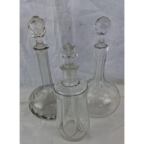 62 - Set of three vintage glass decanters with faceted stoppers. Each decanter features unique etched des... 