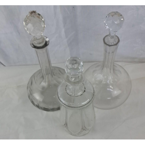 62 - Set of three vintage glass decanters with faceted stoppers. Each decanter features unique etched des... 