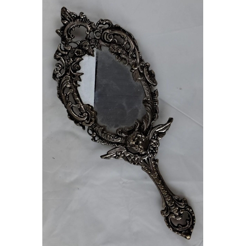 85 - This is an ornate Victorian-style hand mirror with an intricately detailed silver-toned metal frame.... 