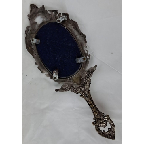 85 - This is an ornate Victorian-style hand mirror with an intricately detailed silver-toned metal frame.... 