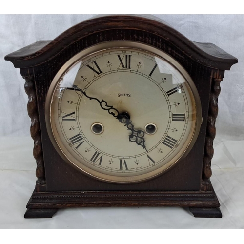 95 - Smiths Mantel Clock is dark wood case with intricate carvings. It features a Roman numeral face and ... 