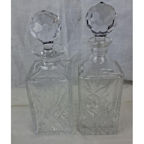 98 - Pair of cut crystal decanters with faceted stoppers and intricate etched designs.