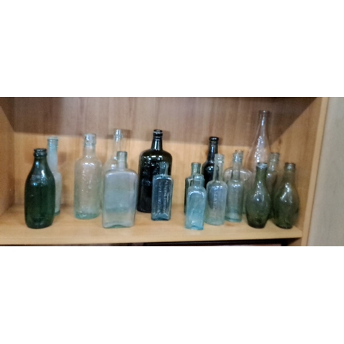 102 - Assortment of 17 vintage glass bottles. The collection includes clear, green, and aqua-colored bottl... 