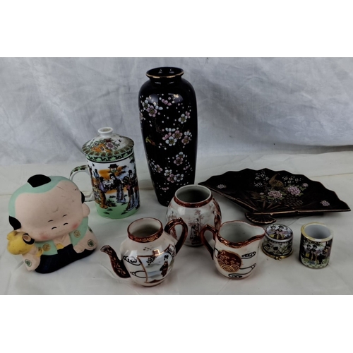 118 - The collection includes a black floral vase, a porcelain figurine, a decorative teapot, two creamers... 