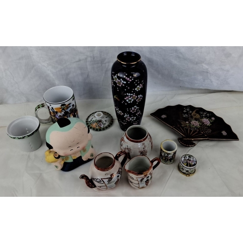 118 - The collection includes a black floral vase, a porcelain figurine, a decorative teapot, two creamers... 