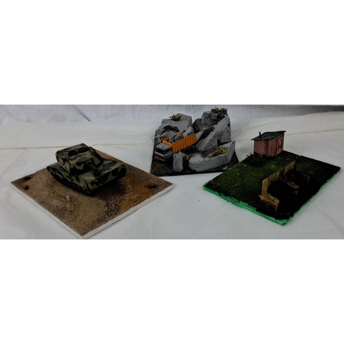 121 - Set of three military diorama models: a camouflaged tank in a desert landscape, a dump truck unloadi... 