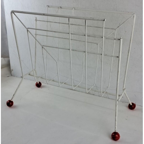 676 - This is a Mid-Century Modern white metal magazine rack on red caster wheels, featuring a geometric d... 