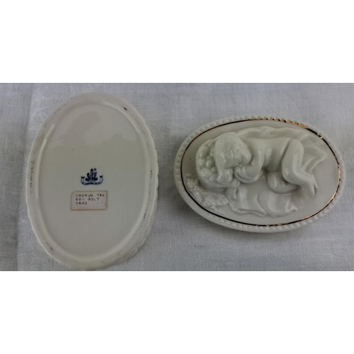 18 - Unusual Belleek trinket box adorned with a cherub and floral design, featuring delicate gilt accents... 