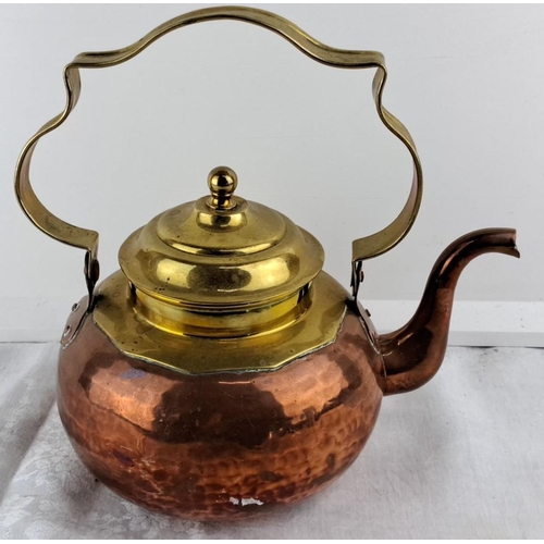 68 - Vintage copper and brass kettle with a hammered texture and ornate handle.