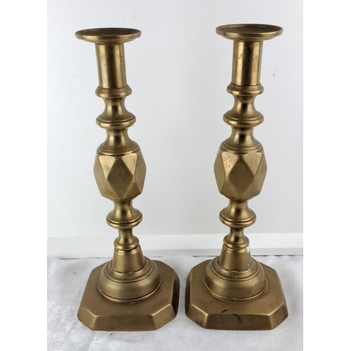 69 - Pair of brass candlesticks with octagonal bases, featuring turned column designs, from the Victorian... 