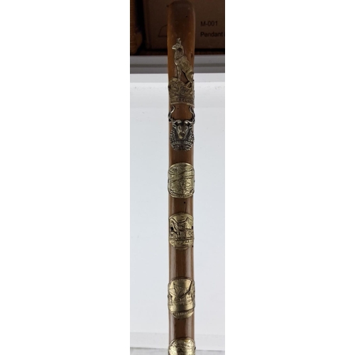 77 - Vintage walking stick adorned with multiple badges from various regions, featuring detailed engravin... 