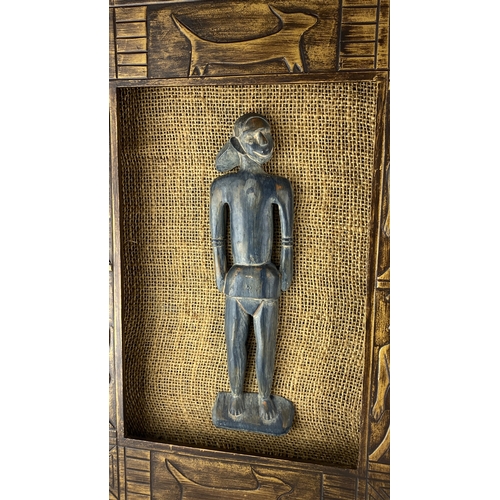 91 - Hand-carved wooden masks and figurines, set in a rustic burlap-backed frame with etched animal motif... 