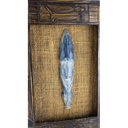 91 - Hand-carved wooden masks and figurines, set in a rustic burlap-backed frame with etched animal motif... 