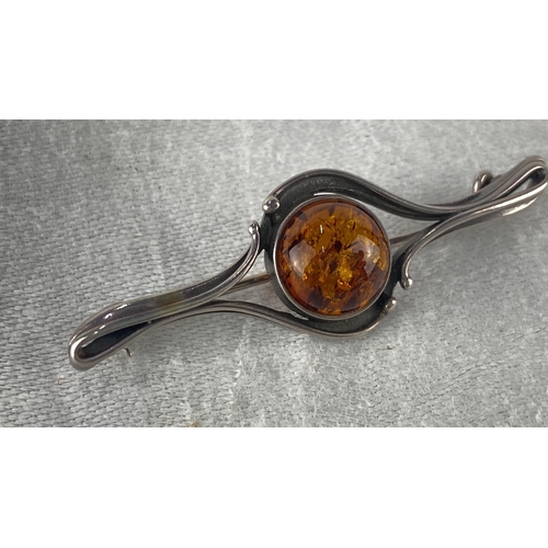 97 - Sterling Silver brooch with an amber gemstone features a swirling design. It is marked 925.