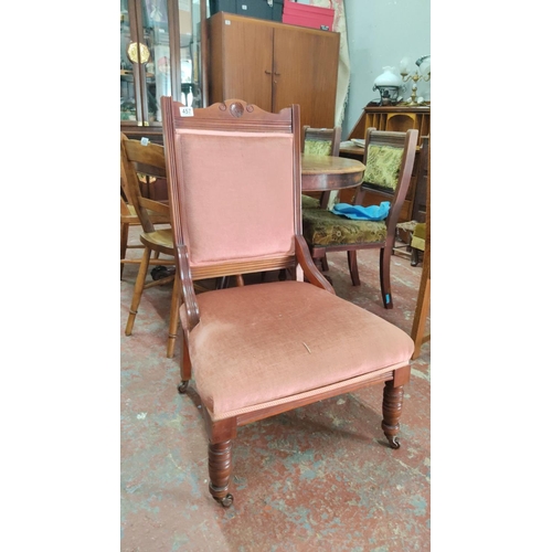 457 - Victorian upholstered mahogany armchair features a carved backrest and turned front legs with caster... 