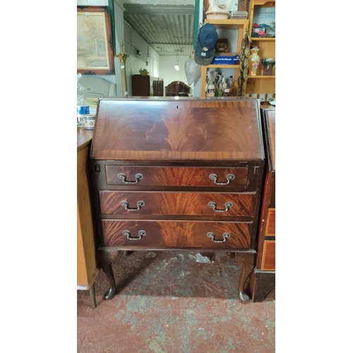 473 - Mahogany writing bureau with three drawers and a drop-down front revealing interior compartments and... 