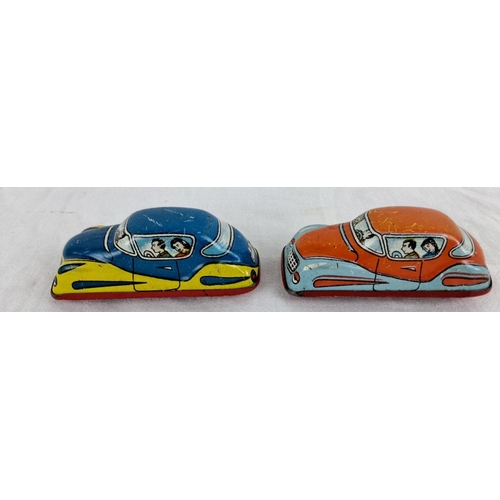 13 - Pair of vintage tin lithograph toy cars with vibrant graphics depicting passengers inside.